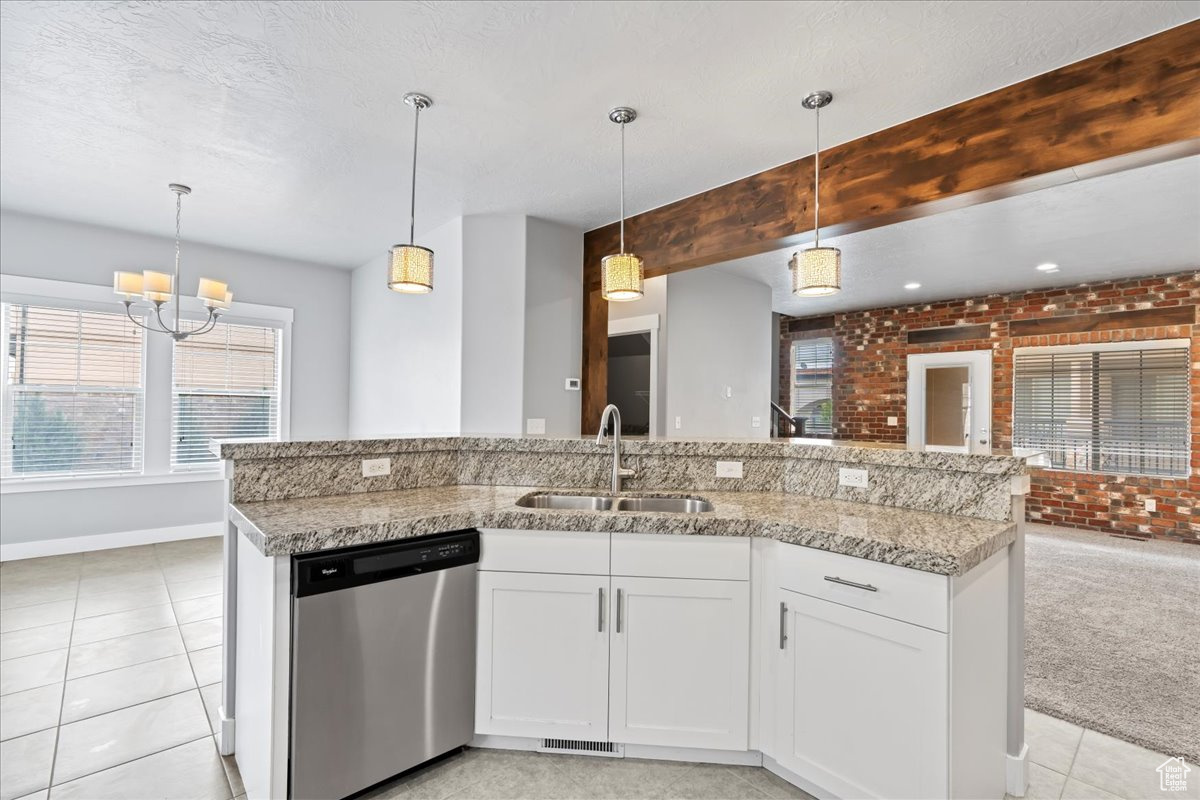 Kitchen with decorative light fixtures, brick wall, sink, light colored carpet, and dishwasher