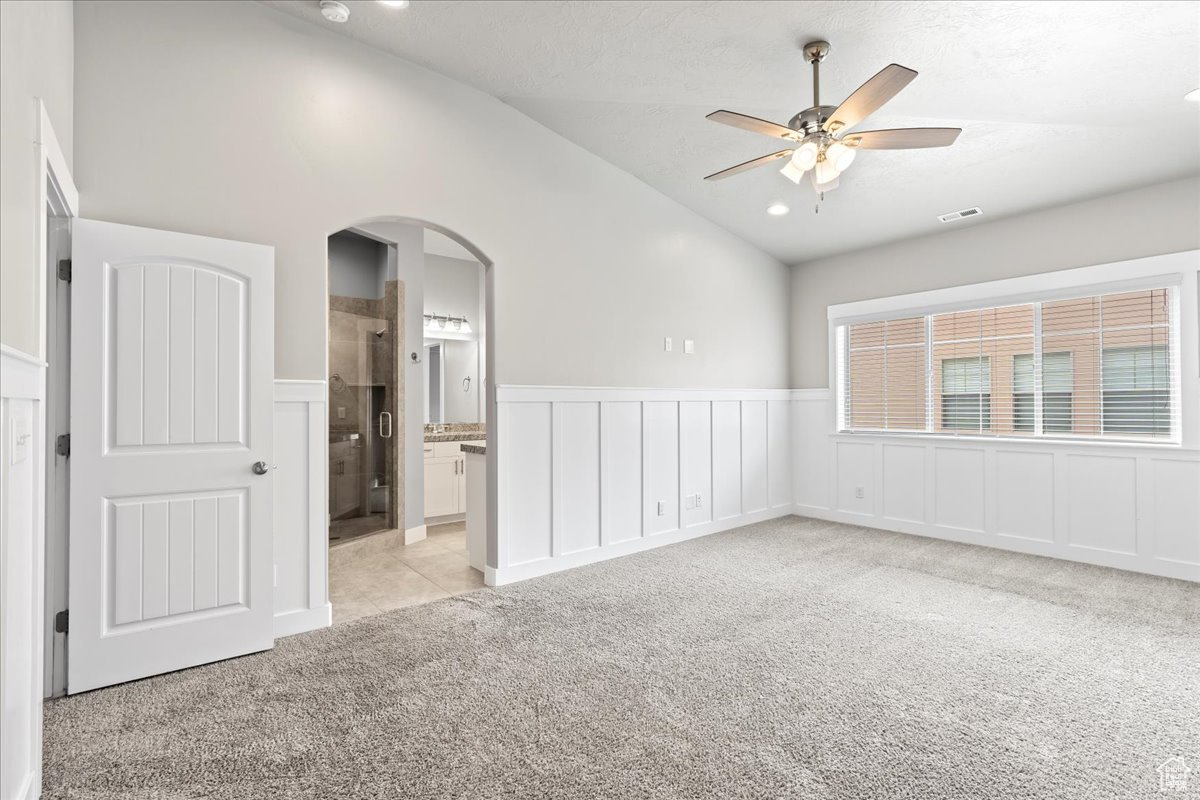 Carpeted spare room featuring high vaulted ceiling and ceiling fan