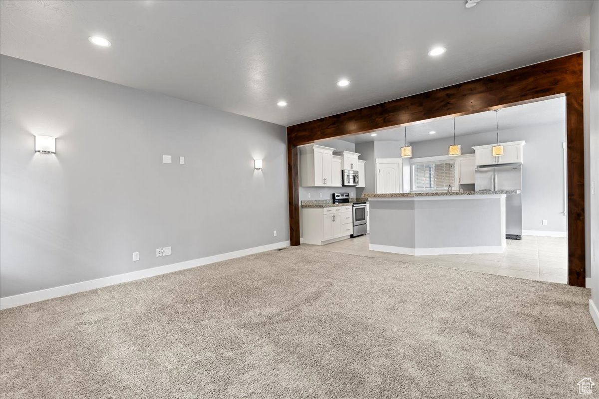 Unfurnished living room with light colored carpet and beam ceiling