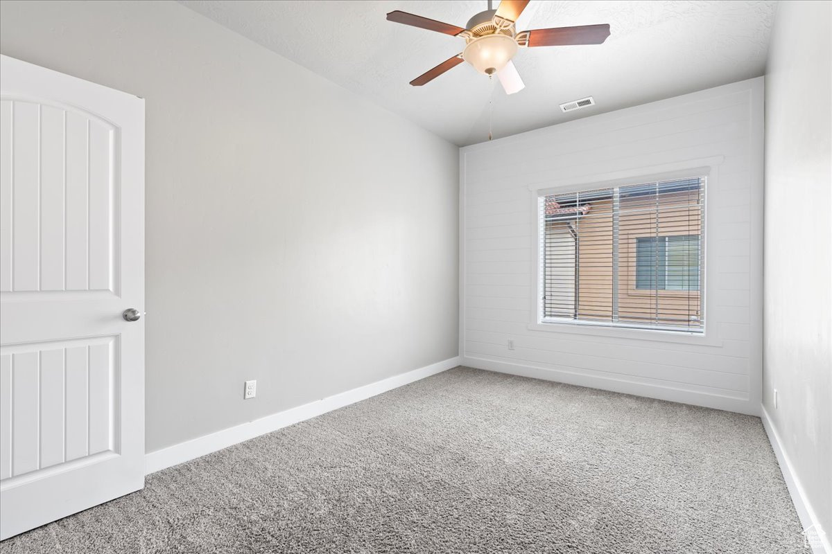 Carpeted spare room with ceiling fan