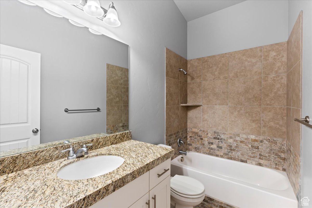 Full bathroom with tiled shower / bath combo, toilet, and vanity