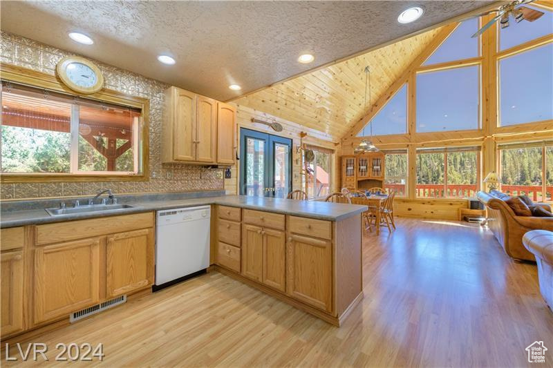 Kitchen with high vaulted ceiling, white dishwasher, a textured ceiling, sink, and light wood-type flooring