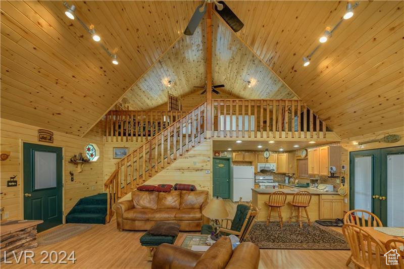 Living room with wood walls, ceiling fan, high vaulted ceiling, and wooden ceiling