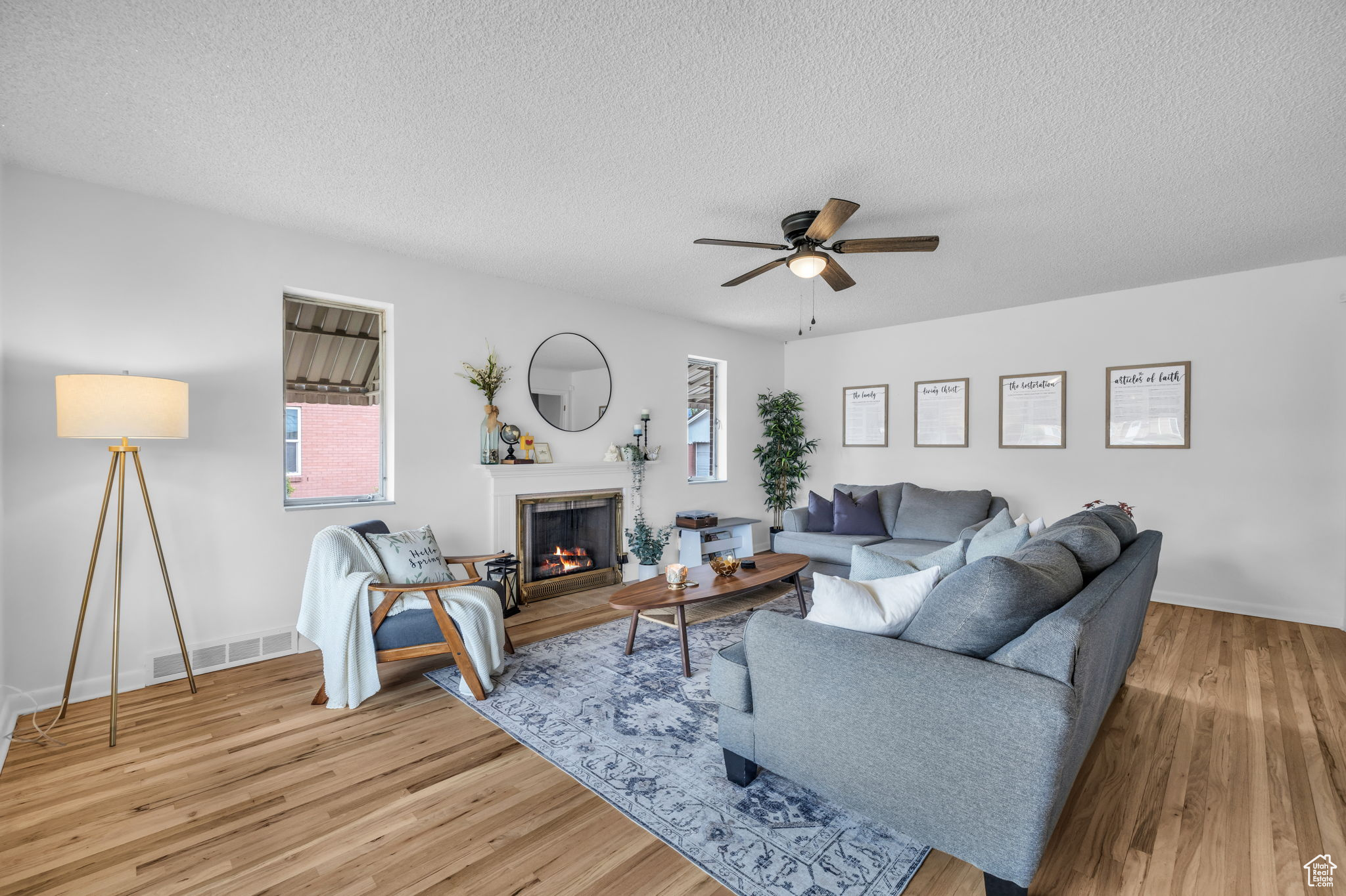 Living room featuring ceiling fan, hardwood / wood-style flooring, and a textured ceiling