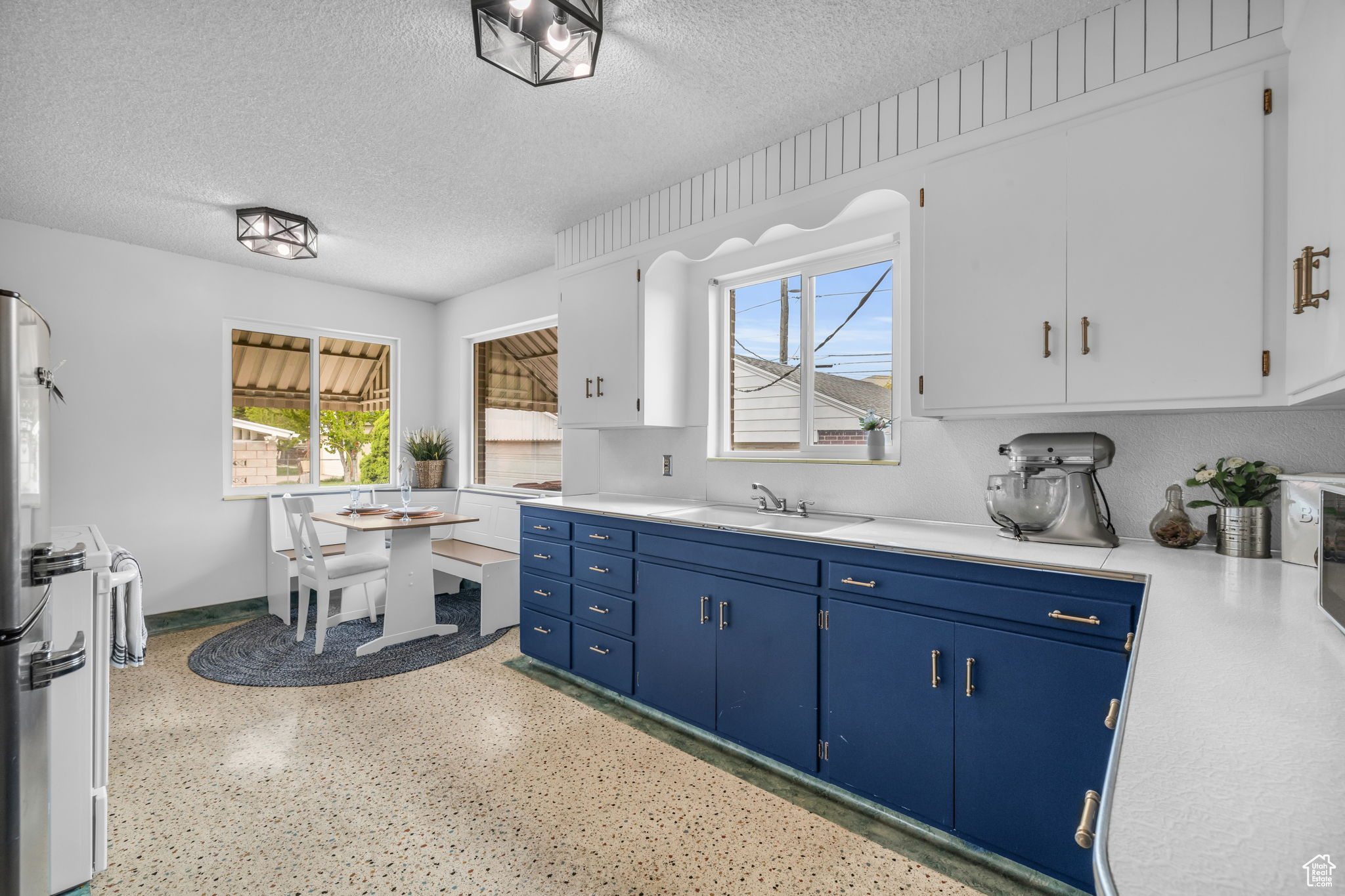 Kitchen featuring a textured ceiling, sink, blue cabinets, and white cabinetry