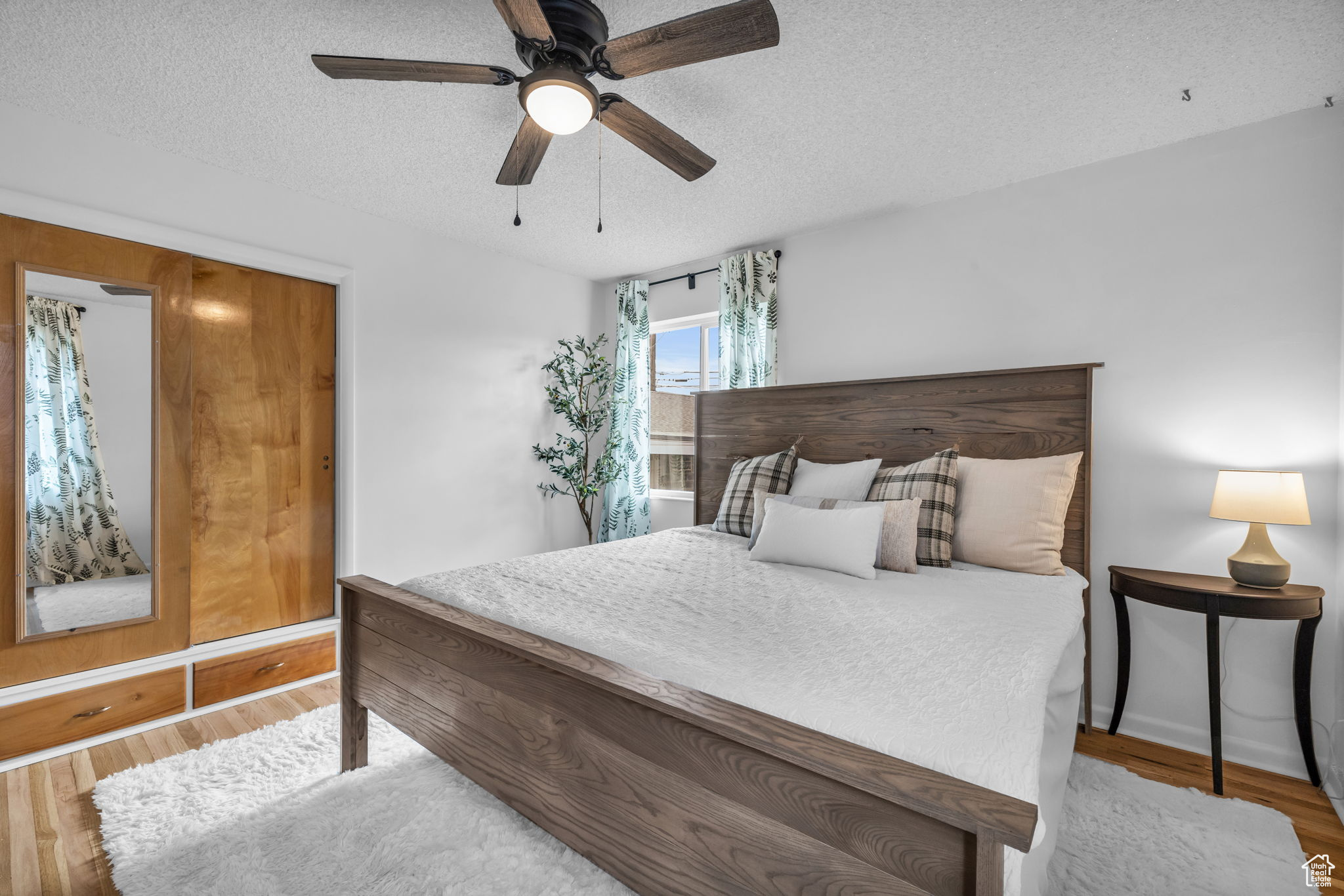 Bedroom with a textured ceiling, ceiling fan, and hardwood / wood-style flooring