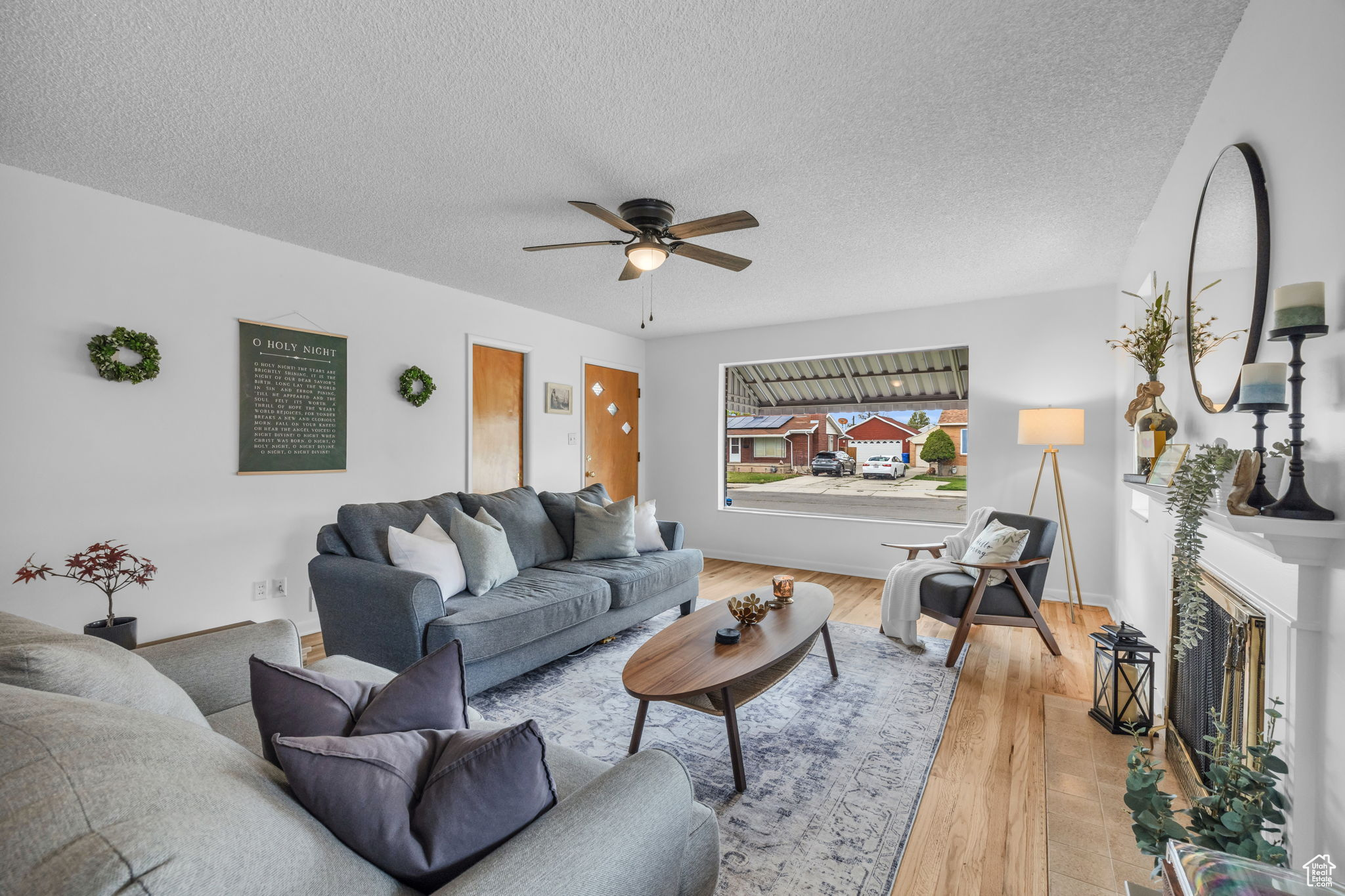 Living room with hardwood / wood-style floors, ceiling fan, and a textured ceiling