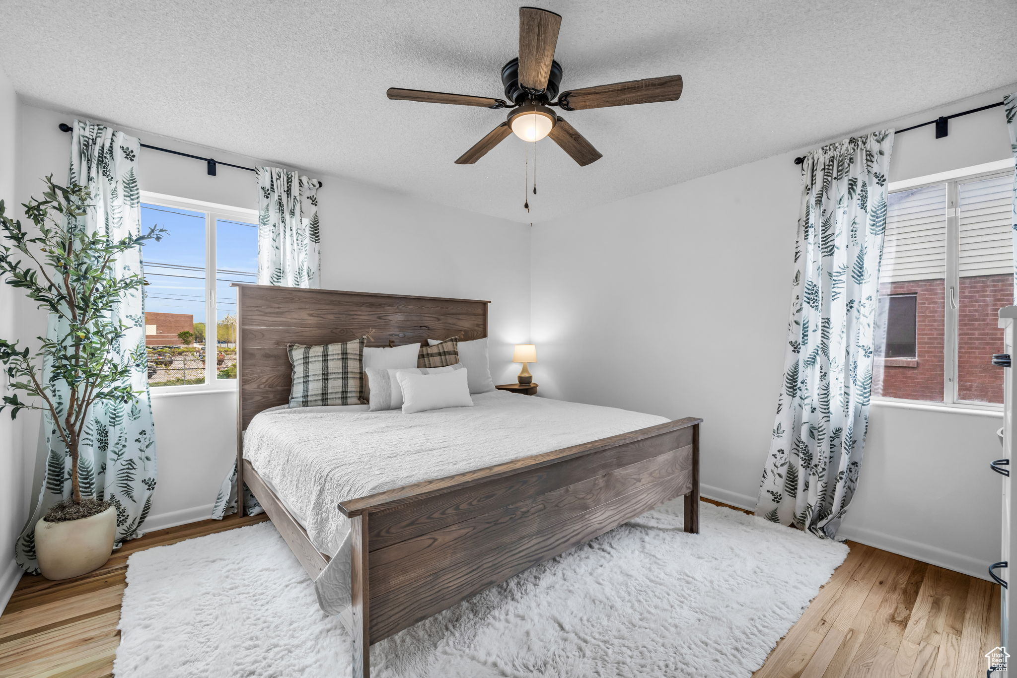 Bedroom featuring light hardwood / wood-style flooring, ceiling fan, and a textured ceiling