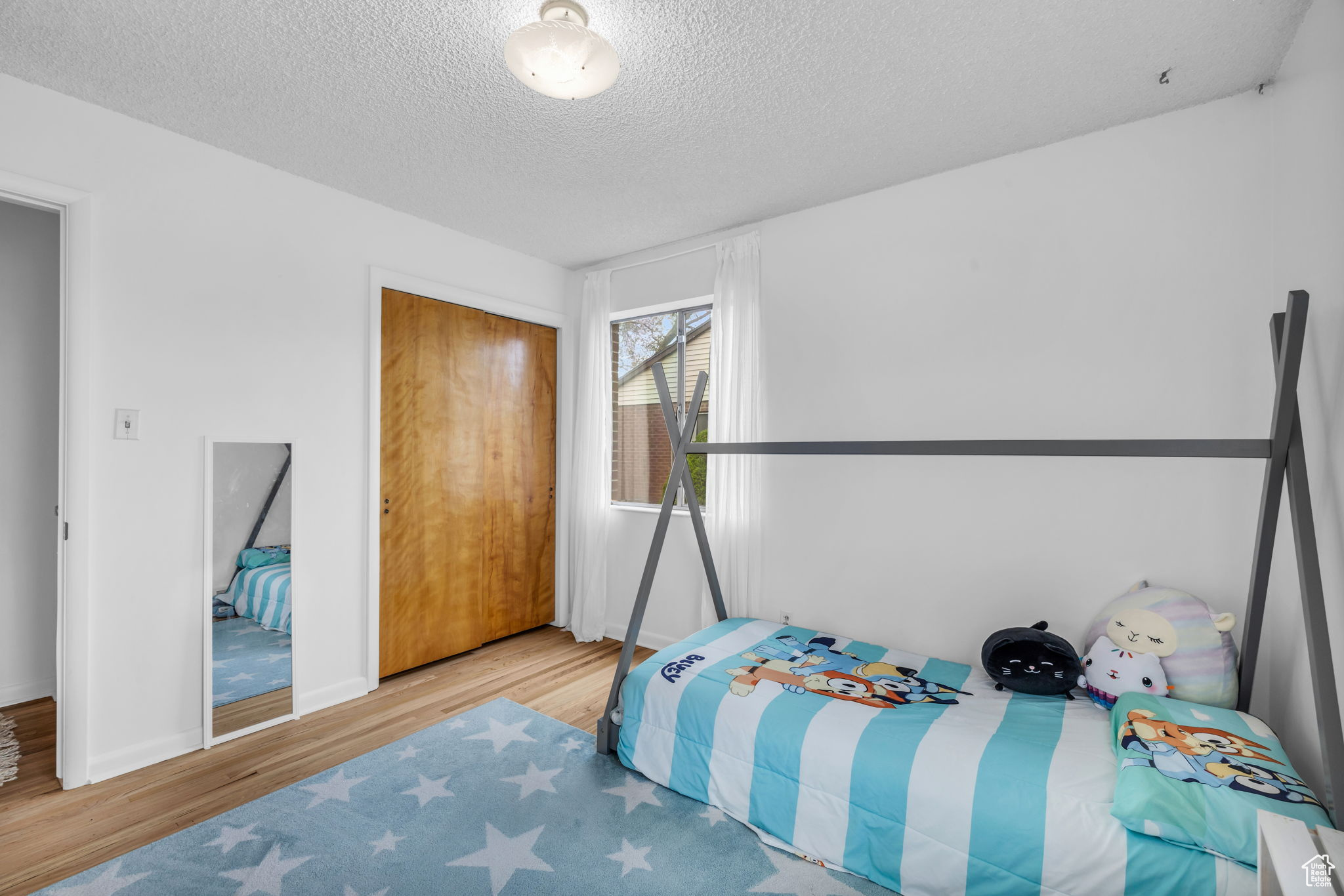 Bedroom featuring light hardwood / wood-style flooring, a closet, and a textured ceiling