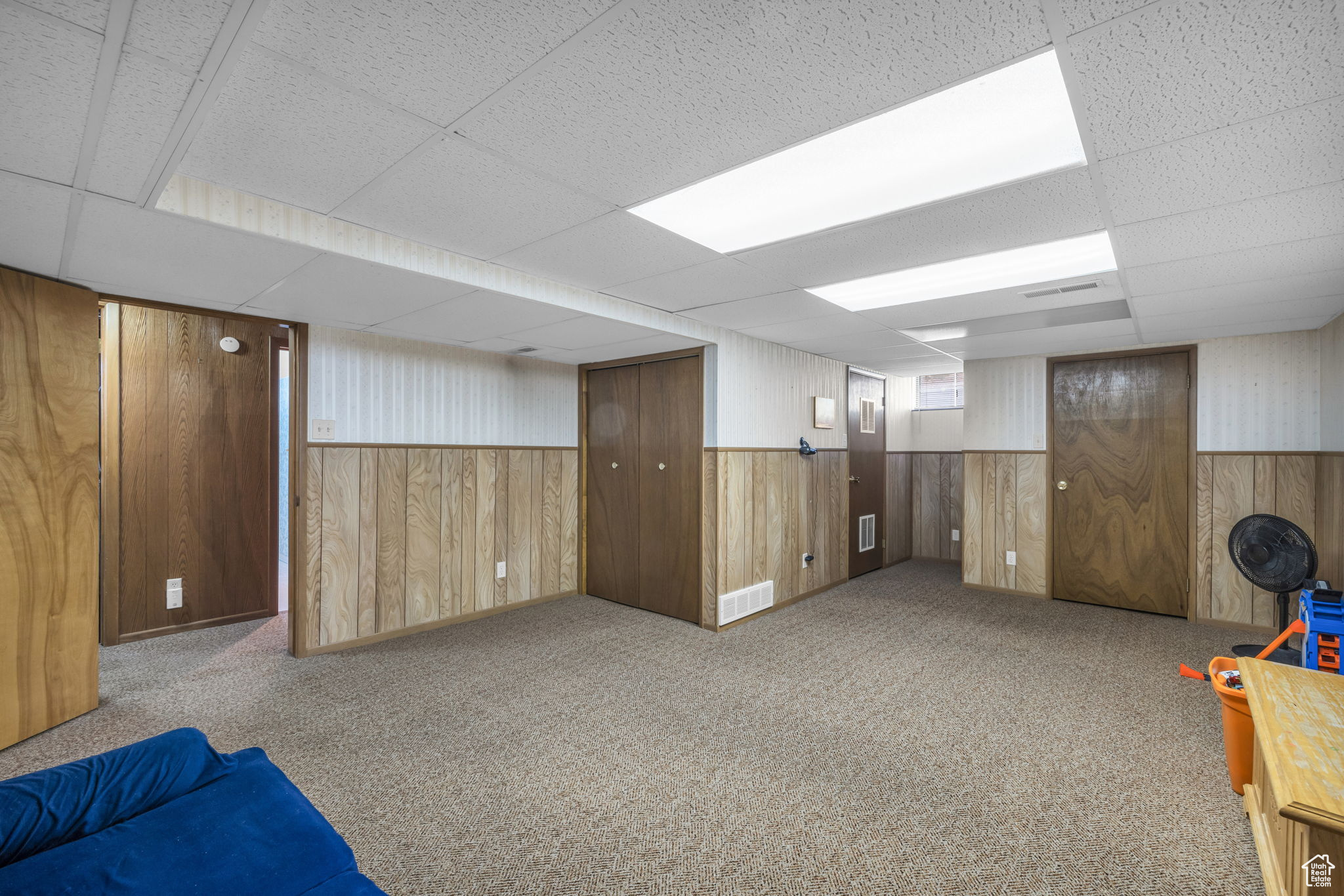 Basement featuring a paneled ceiling, wooden walls, and carpet floors