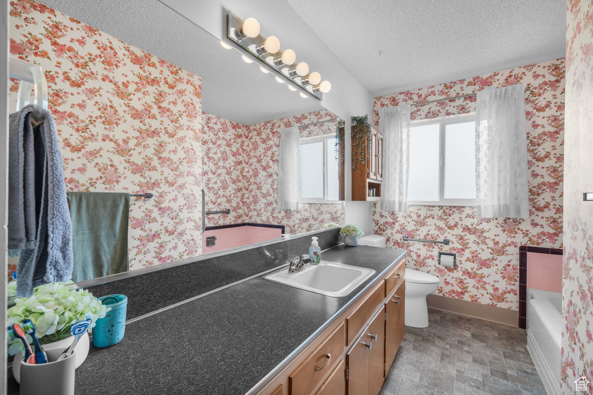 Bathroom with tile floors, a bathing tub, oversized vanity, toilet, and a textured ceiling