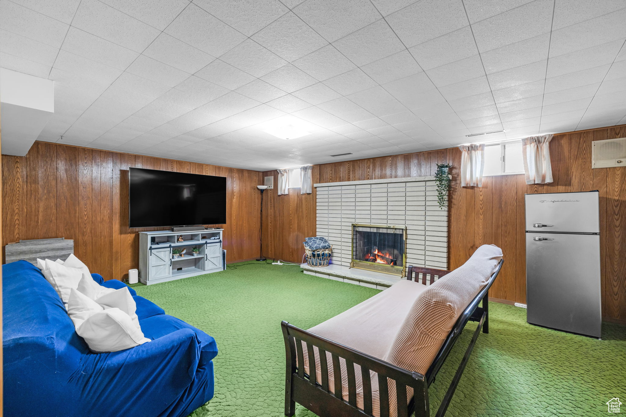 Living room with a fireplace, carpet, and wooden walls