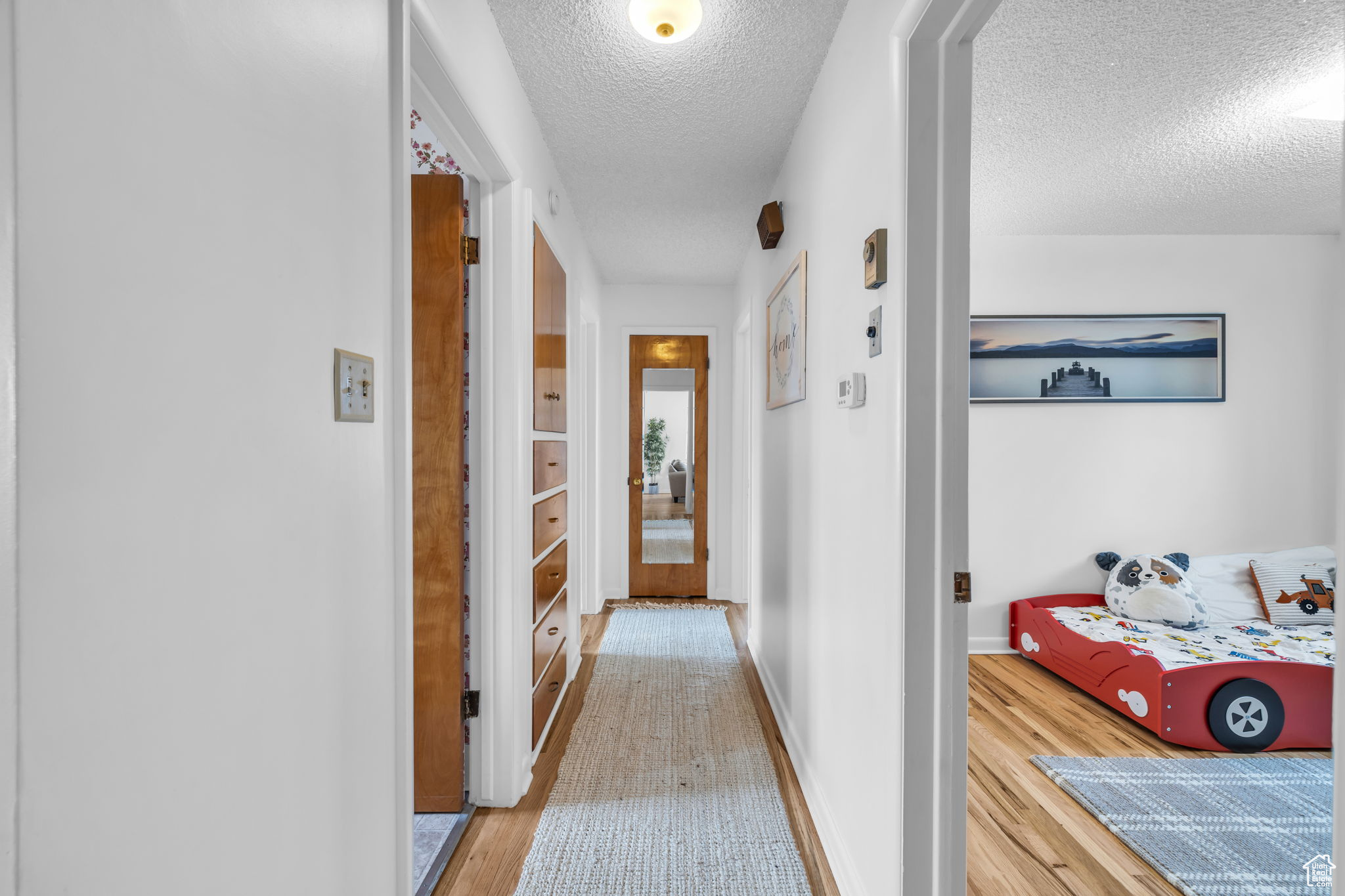 Hallway featuring a textured ceiling and hardwood / wood-style floors