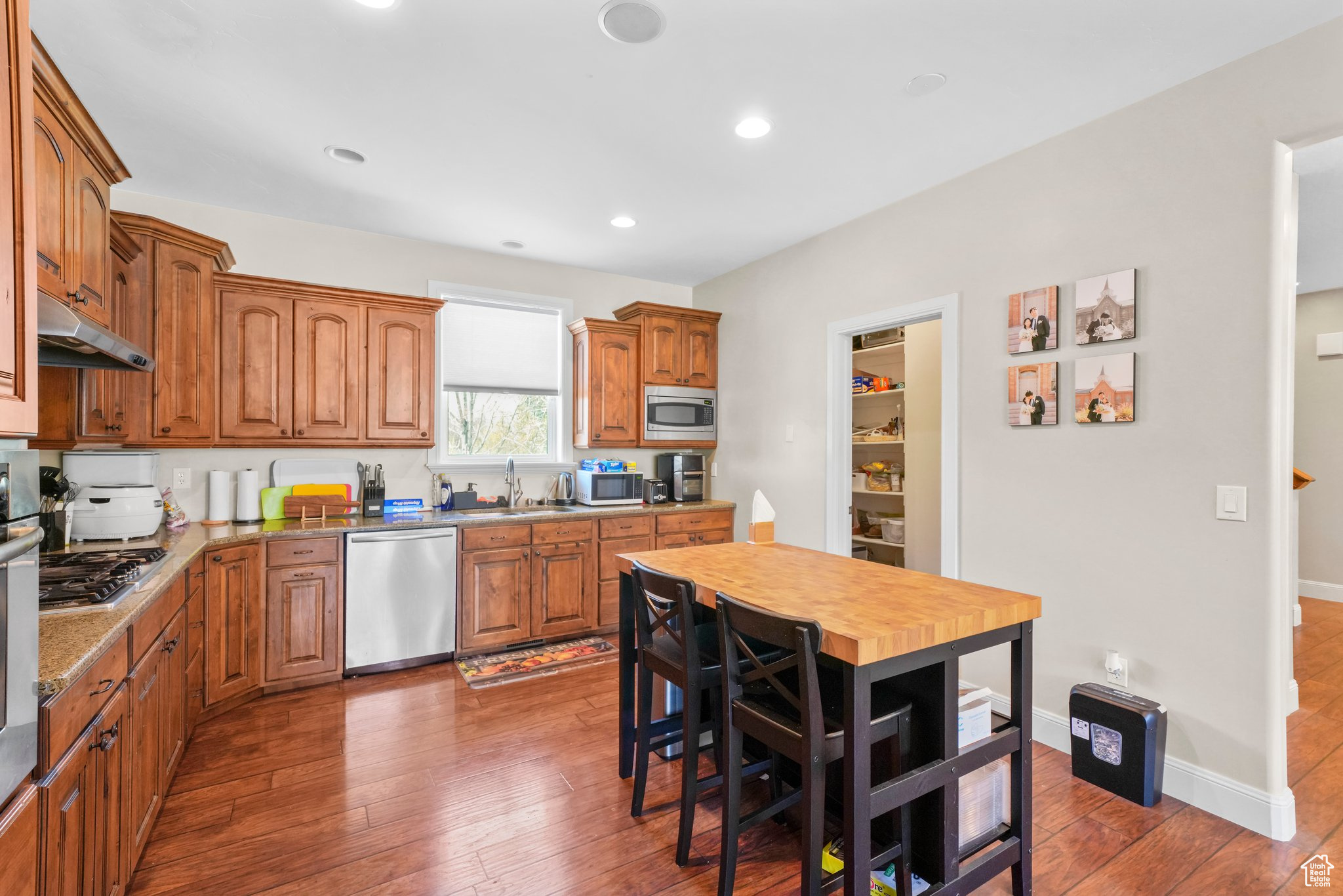 Kitchen featuring sink, appliances with stainless steel finishes, hardwood / wood-style floors, and light stone counters