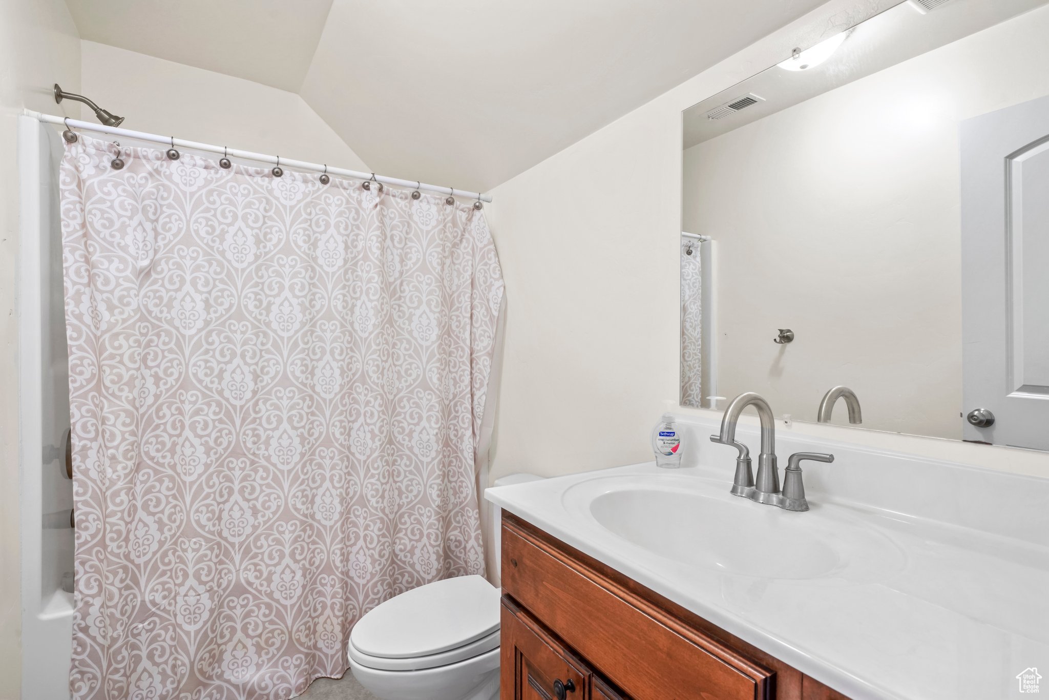 Bathroom with vaulted ceiling, vanity, and toilet