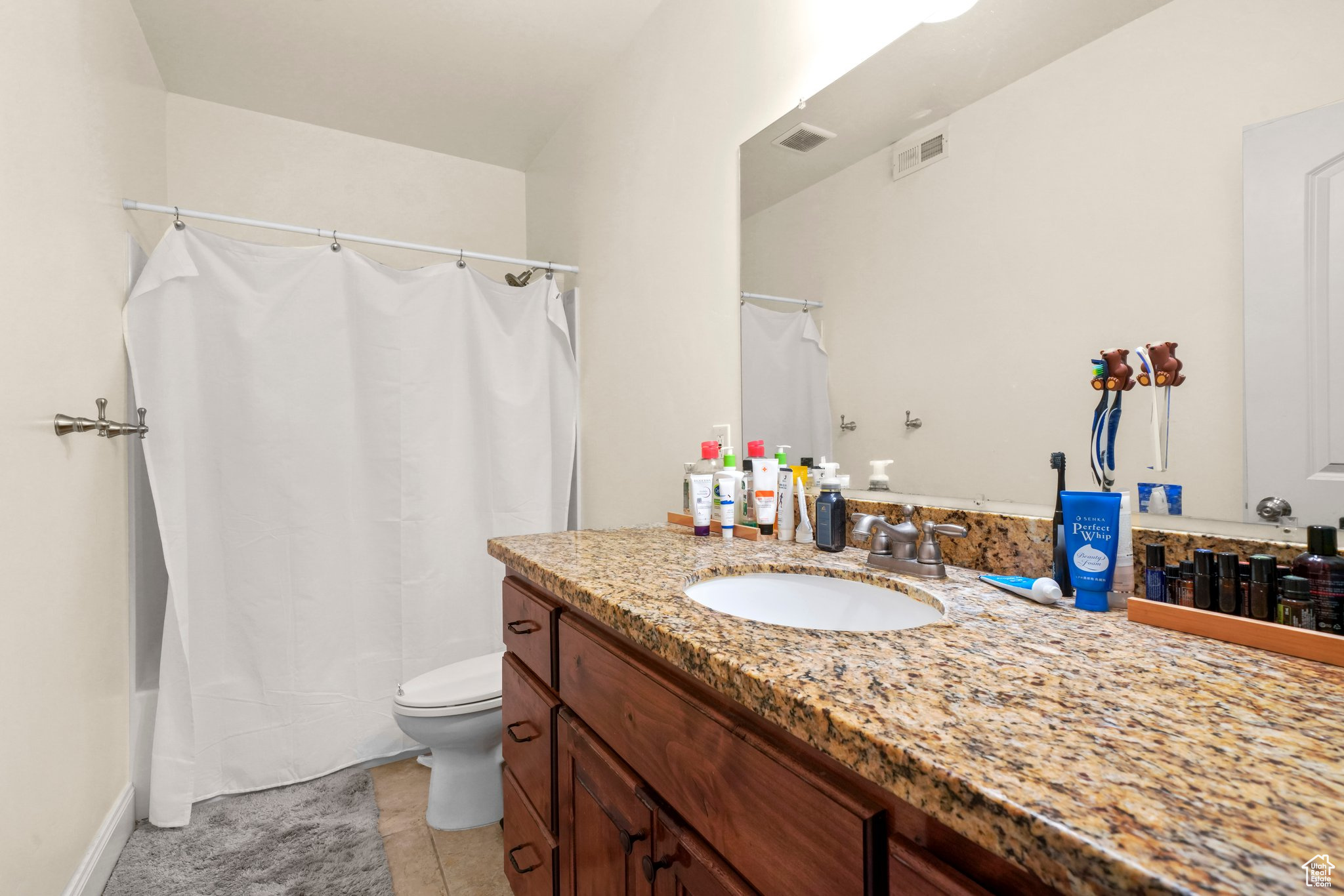 Full bathroom featuring vanity, tile floors, toilet, and shower / bath combination with curtain