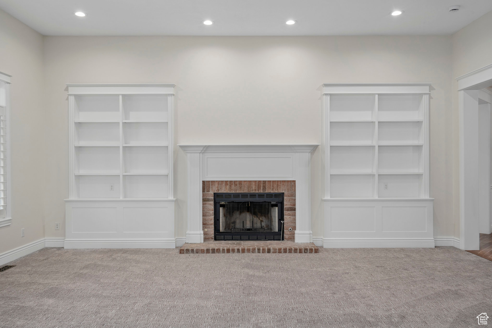 Unfurnished living room with carpet and a brick fireplace