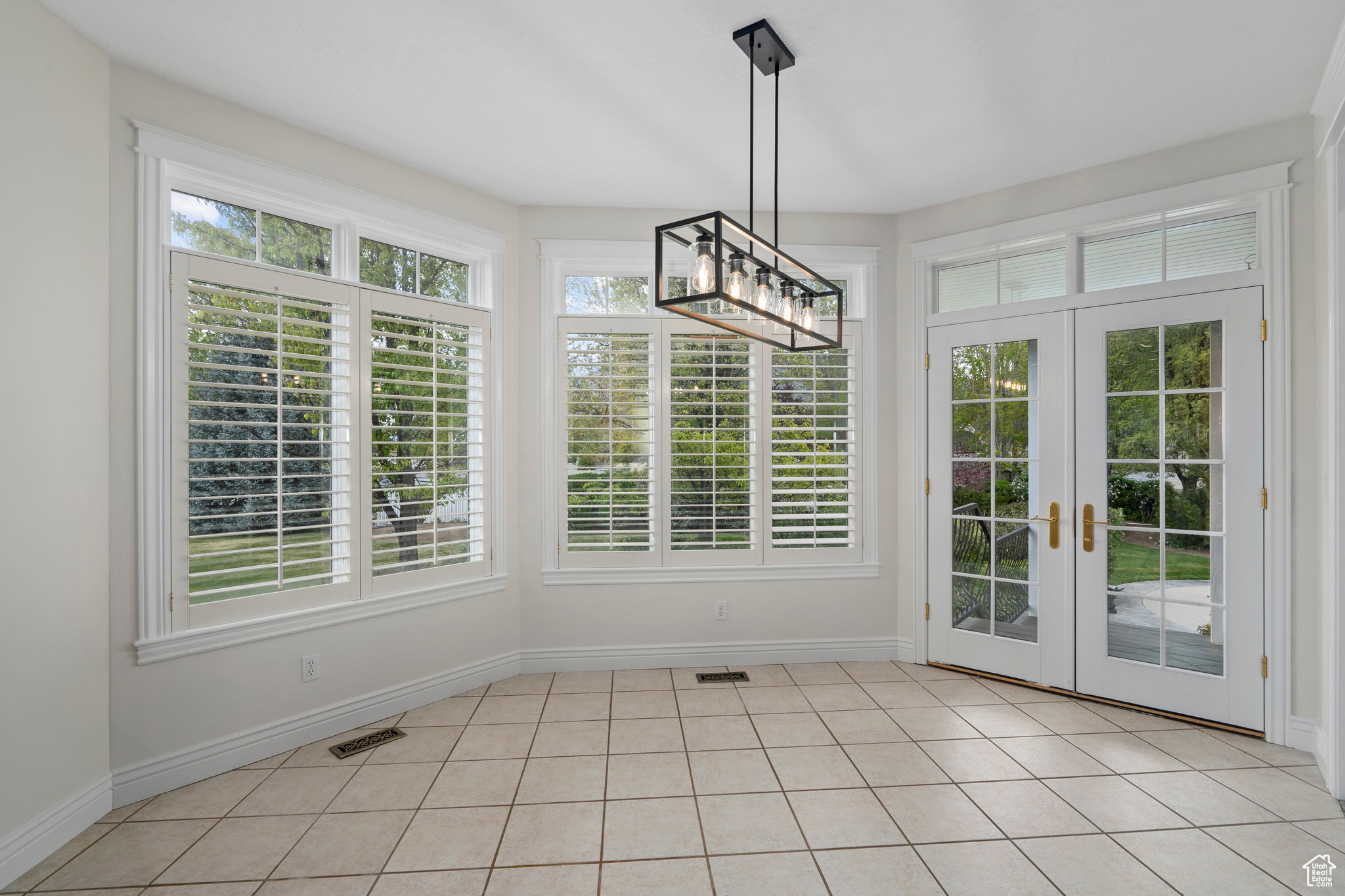 Unfurnished dining area featuring french doors, a healthy amount of sunlight, and light tile floors