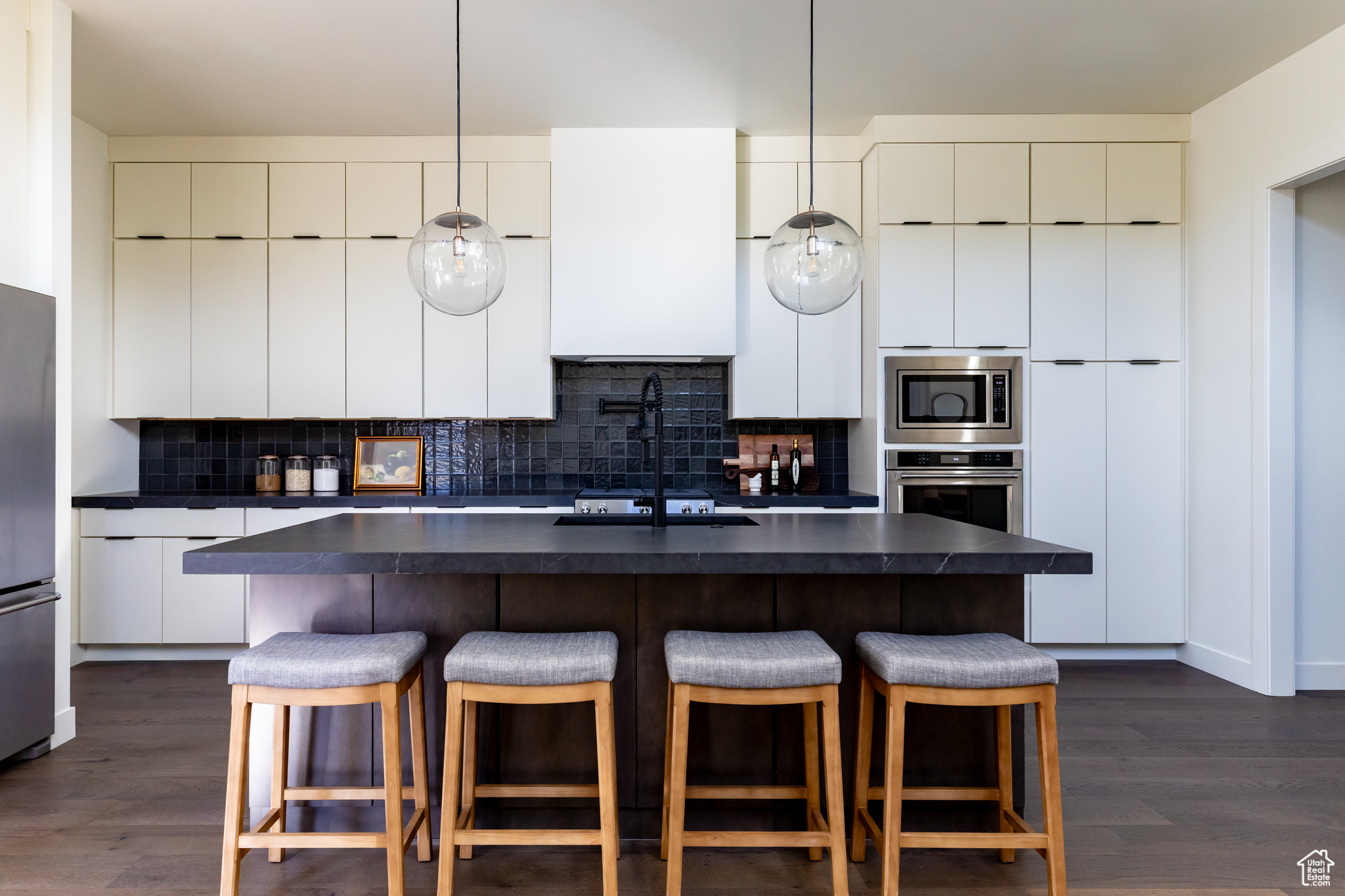 Kitchen with tasteful backsplash, pendant lighting, stainless steel appliances, and dark hardwood / wood-style floors