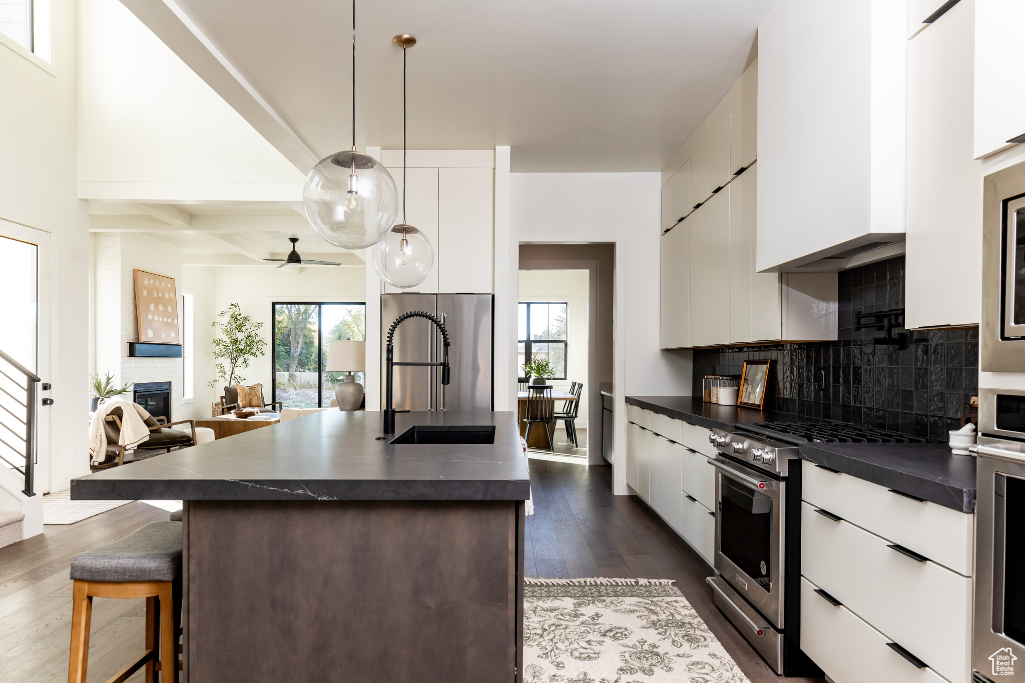 Kitchen with backsplash, stainless steel appliances, ceiling fan, dark wood-type flooring, and sink
