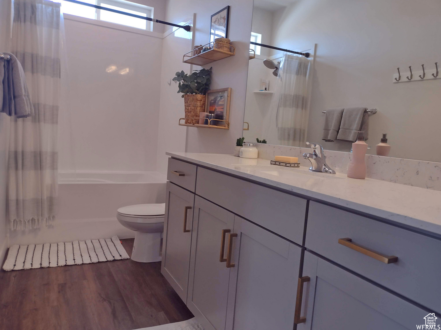 Full bathroom with shower / bathtub combination with curtain, wood-type flooring, vanity, and toilet