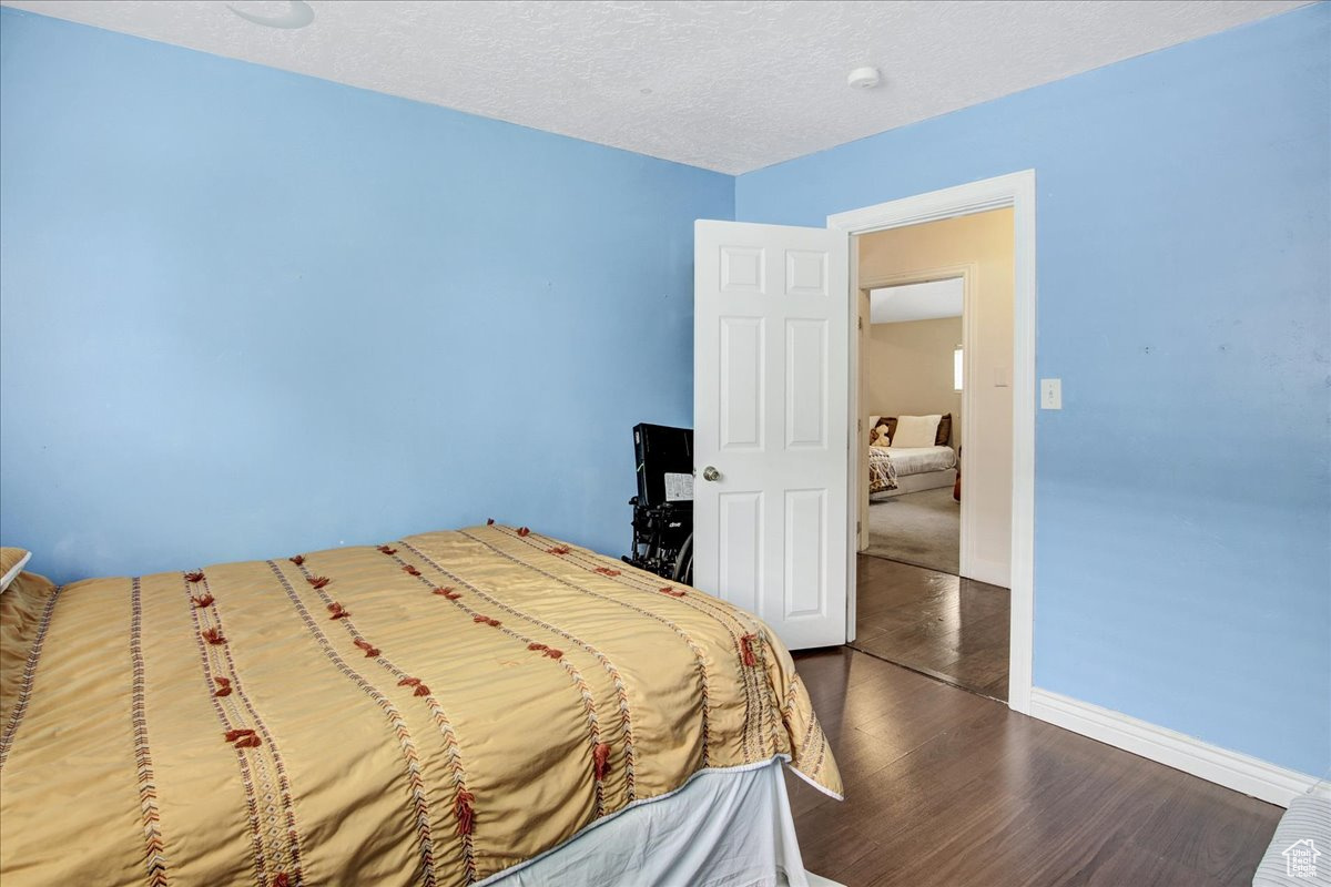 Bedroom with dark hardwood / wood-style floors and a textured ceiling