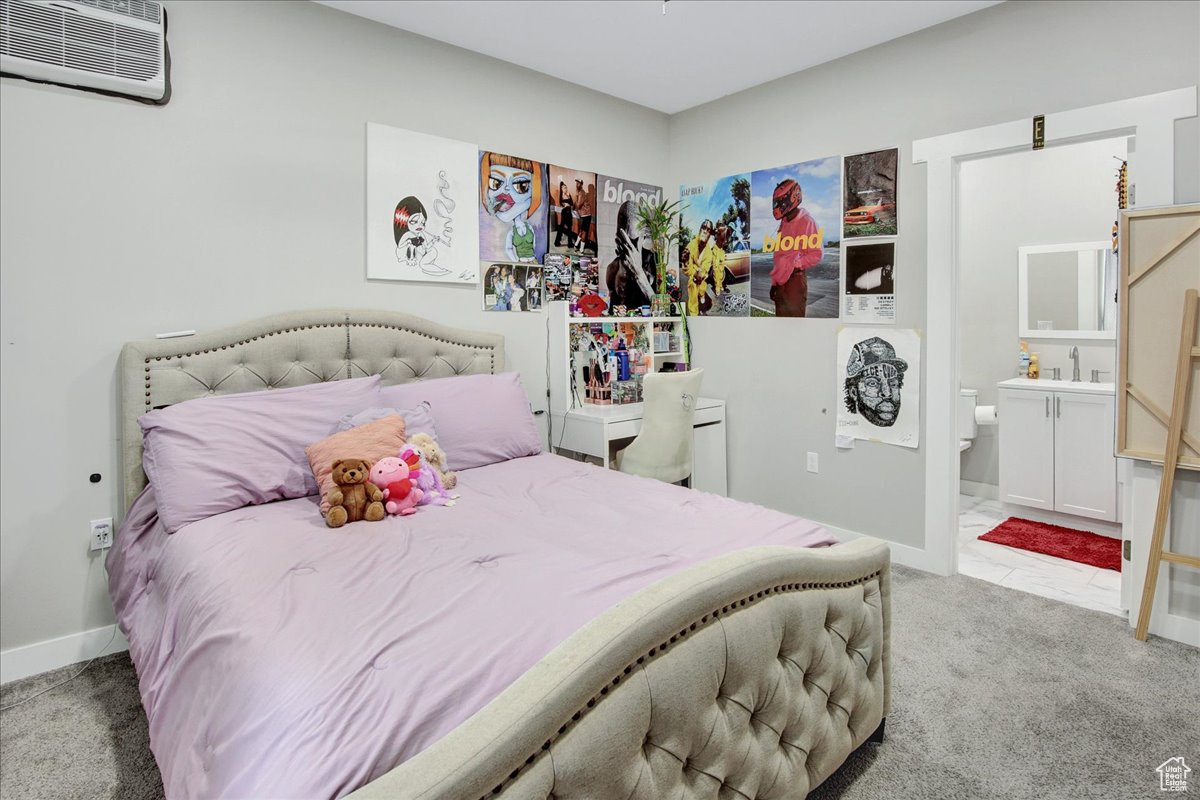 Carpeted bedroom with an AC wall unit, sink, and ensuite bathroom