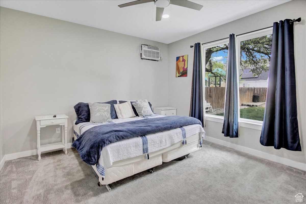 Bedroom with ceiling fan, carpet flooring, and a wall unit AC