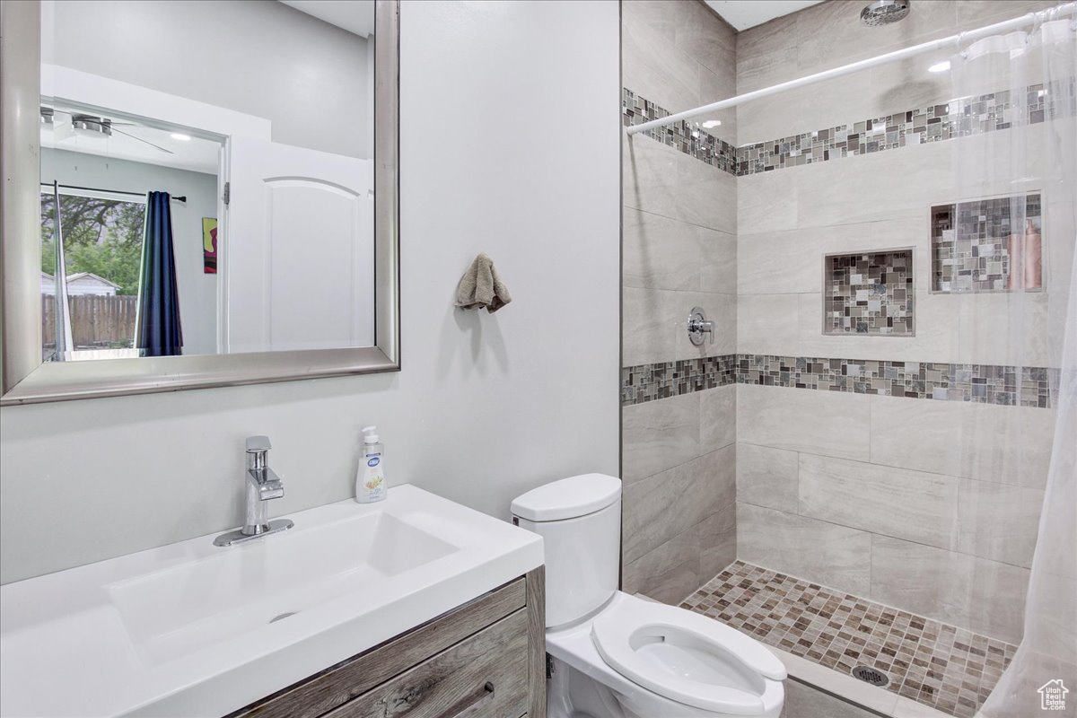 Bathroom with curtained shower, vanity, and toilet