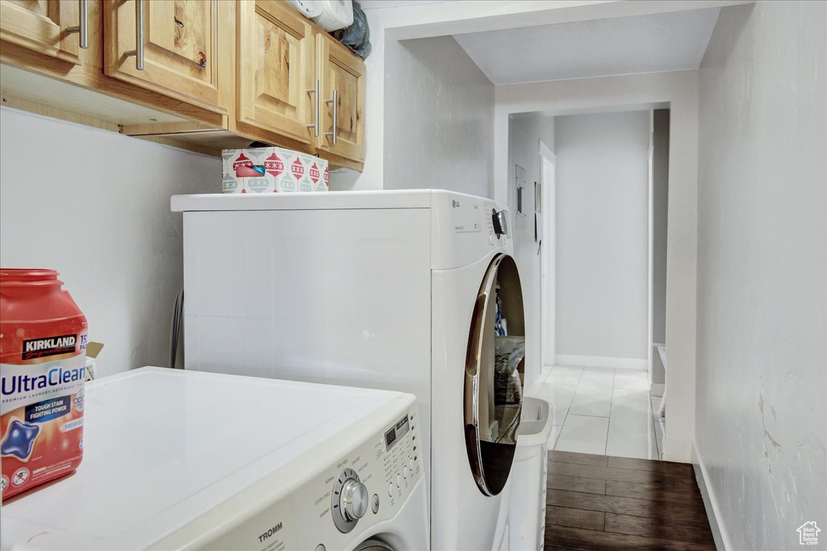 Laundry area with cabinets, light tile floors, and washer and dryer