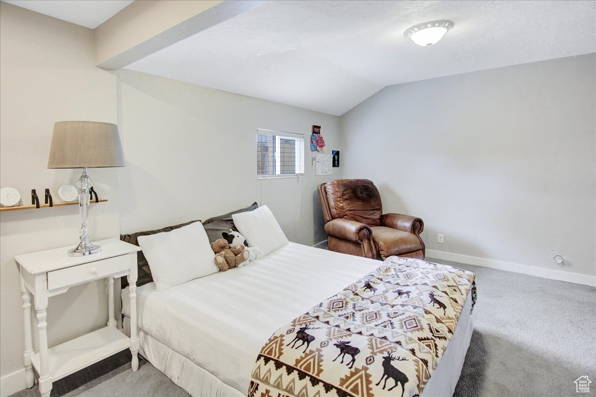 Carpeted bedroom featuring lofted ceiling