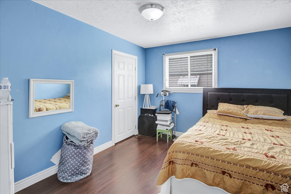 Bedroom with dark hardwood / wood-style flooring and a textured ceiling