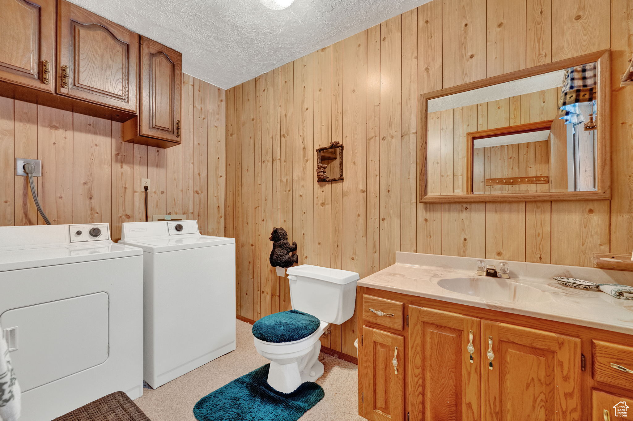 Bathroom featuring large vanity, a textured ceiling, independent washer and dryer, wooden walls, and toilet