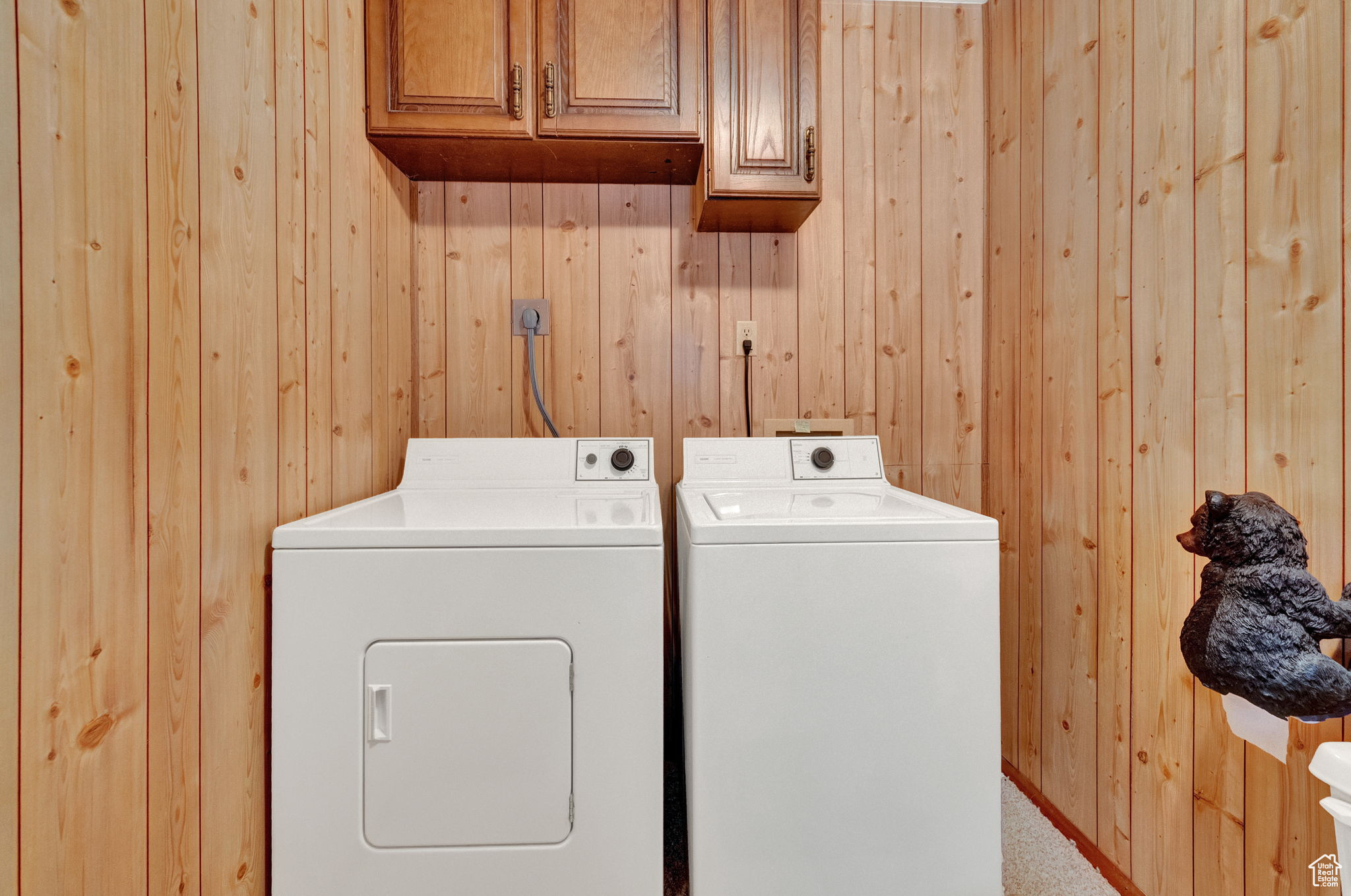 Clothes washing area with cabinets, washing machine and dryer, and wooden walls