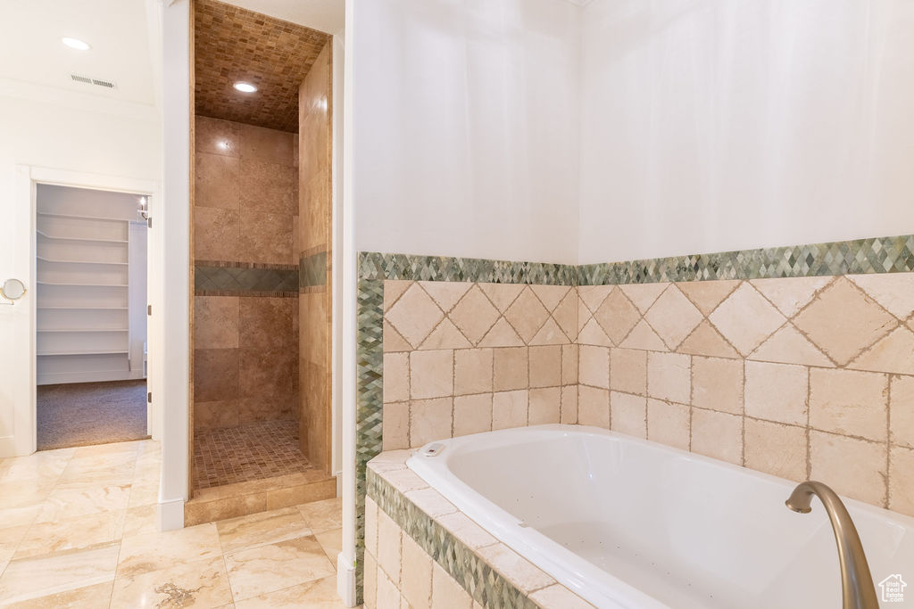 Bathroom featuring tile flooring, crown molding, and plus walk in shower