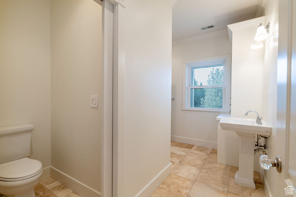 Bathroom with crown molding, toilet, and tile flooring