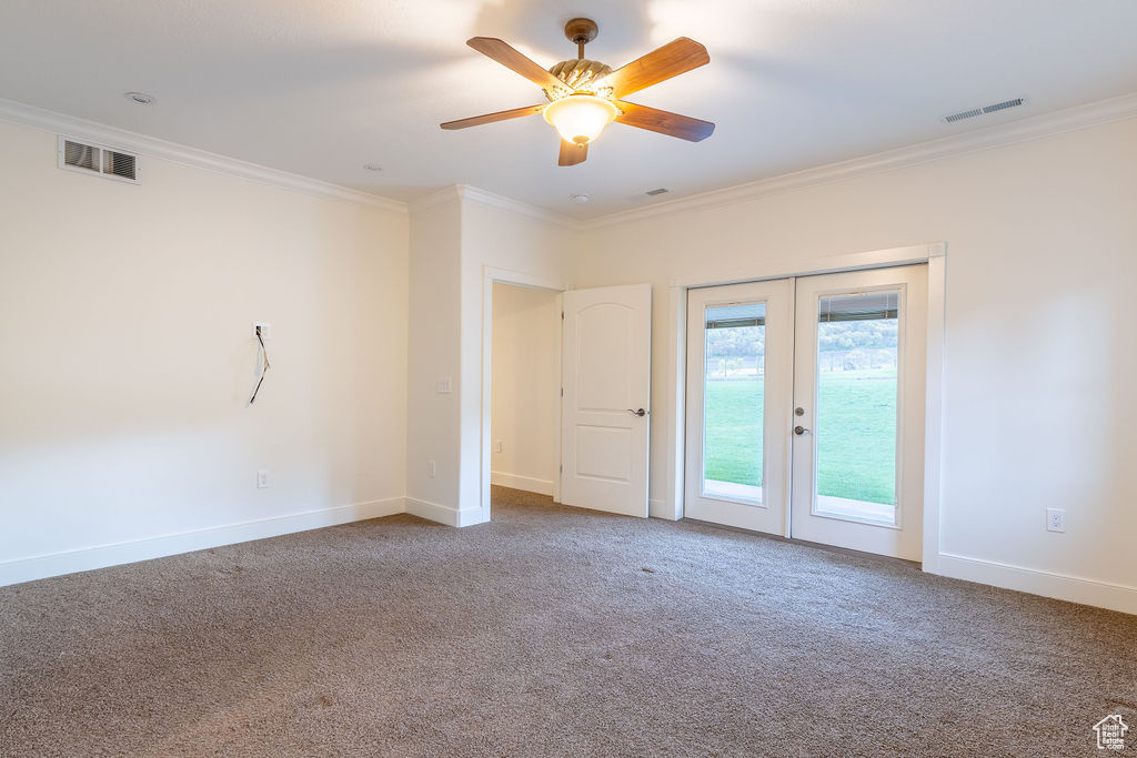 Carpeted spare room with ornamental molding, french doors, and ceiling fan