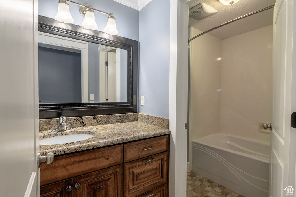 Bathroom with crown molding, washtub / shower combination, tile flooring, and vanity