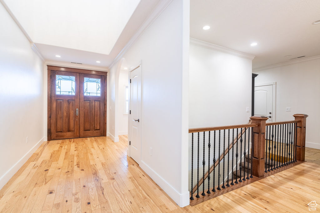 Foyer entrance featuring crown molding and light hardwood / wood-style floors