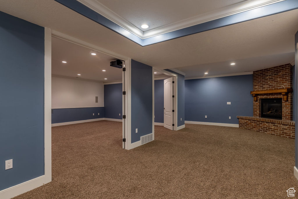 Basement with ornamental molding, carpet, and a fireplace