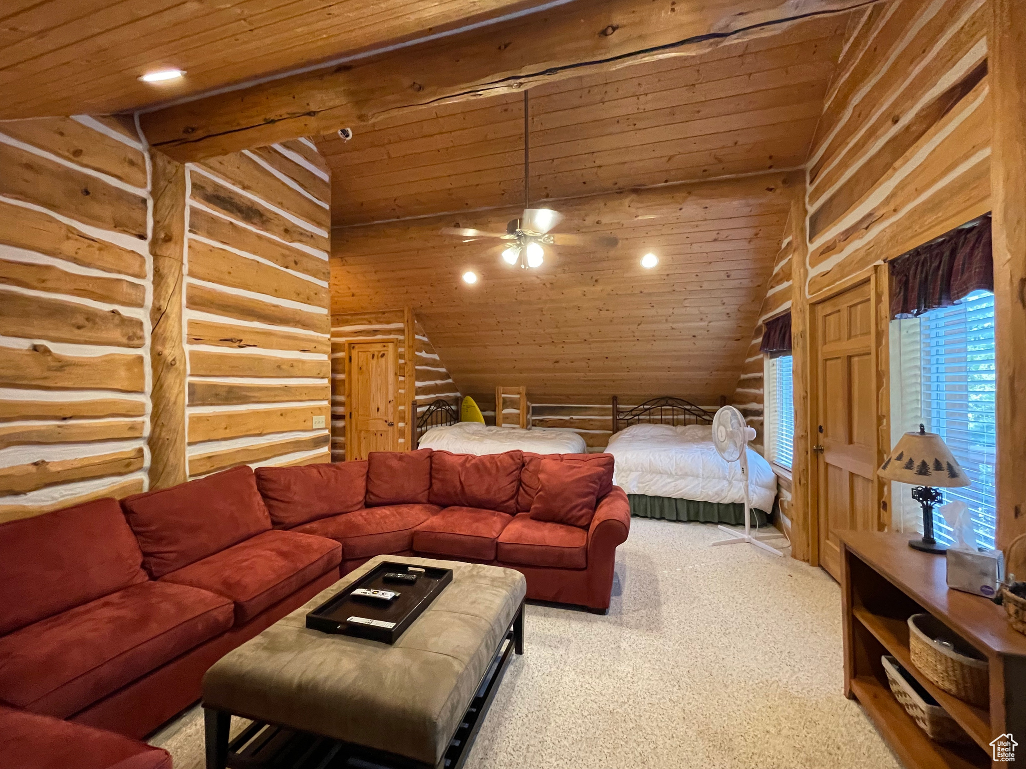 Bedroom/media room with wood ceiling, carpet flooring, high vaulted ceiling, and rustic walls