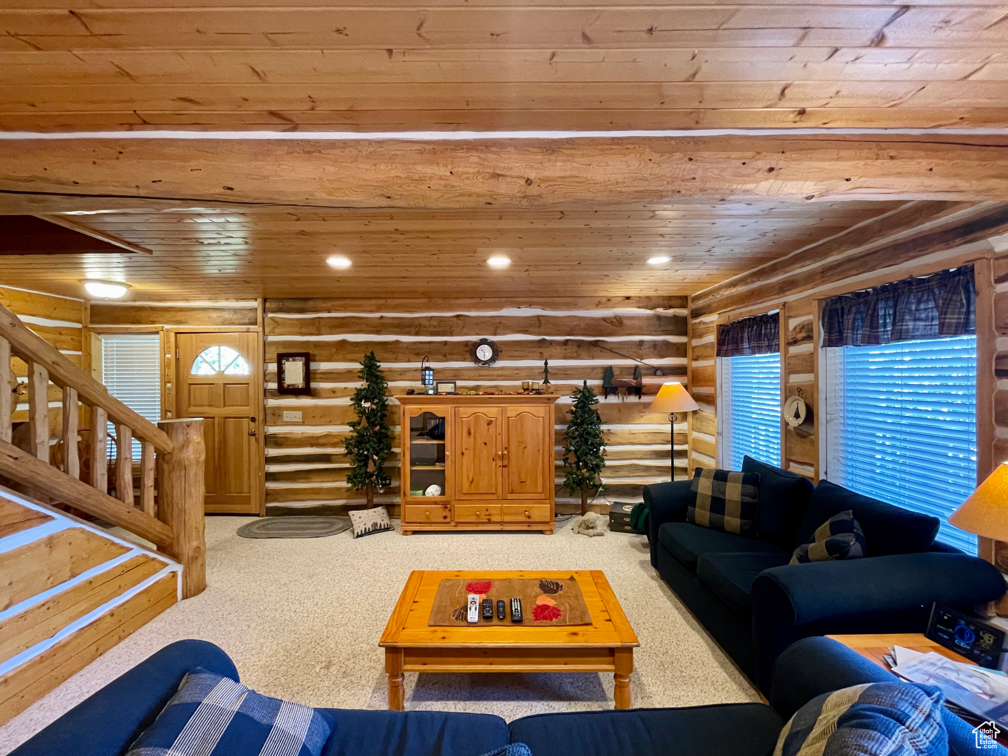 Living room featuring wooden ceiling, log walls, and light colored carpet