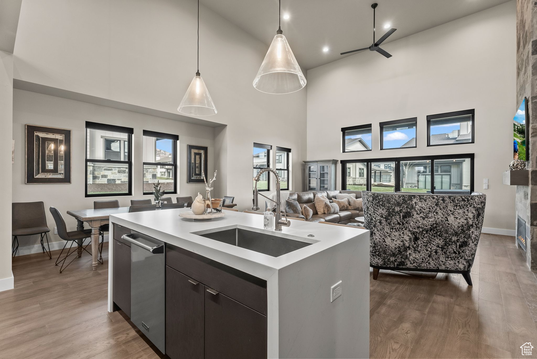 Kitchen featuring decorative light fixtures, hardwood / wood-style floors, a towering ceiling, sink, and stainless steel dishwasher