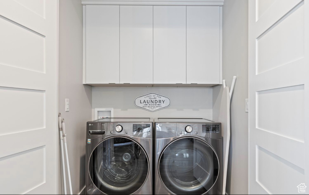 Clothes washing area with washer and clothes dryer, cabinets, and washer hookup