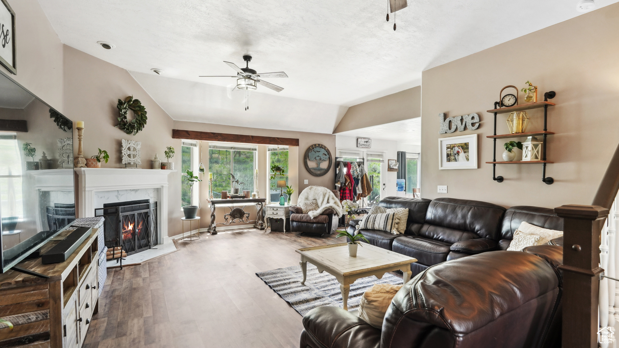 Living room featuring hardwood / wood-style floors, vaulted ceiling, ceiling fan, and a high end fireplace