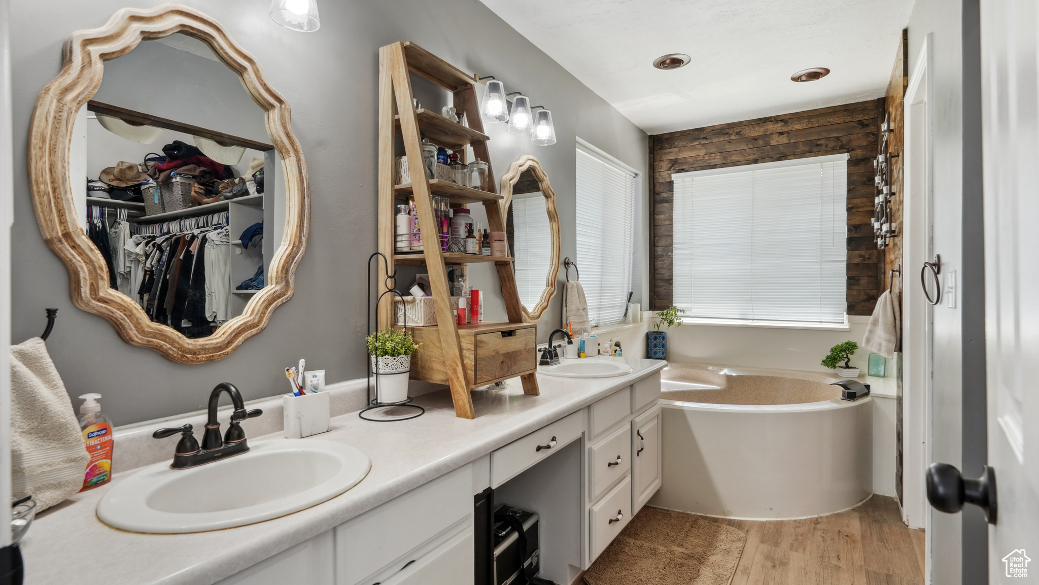 Primary bathroom with large vanity, a washtub, hardwood / wood-style flooring, and double sink