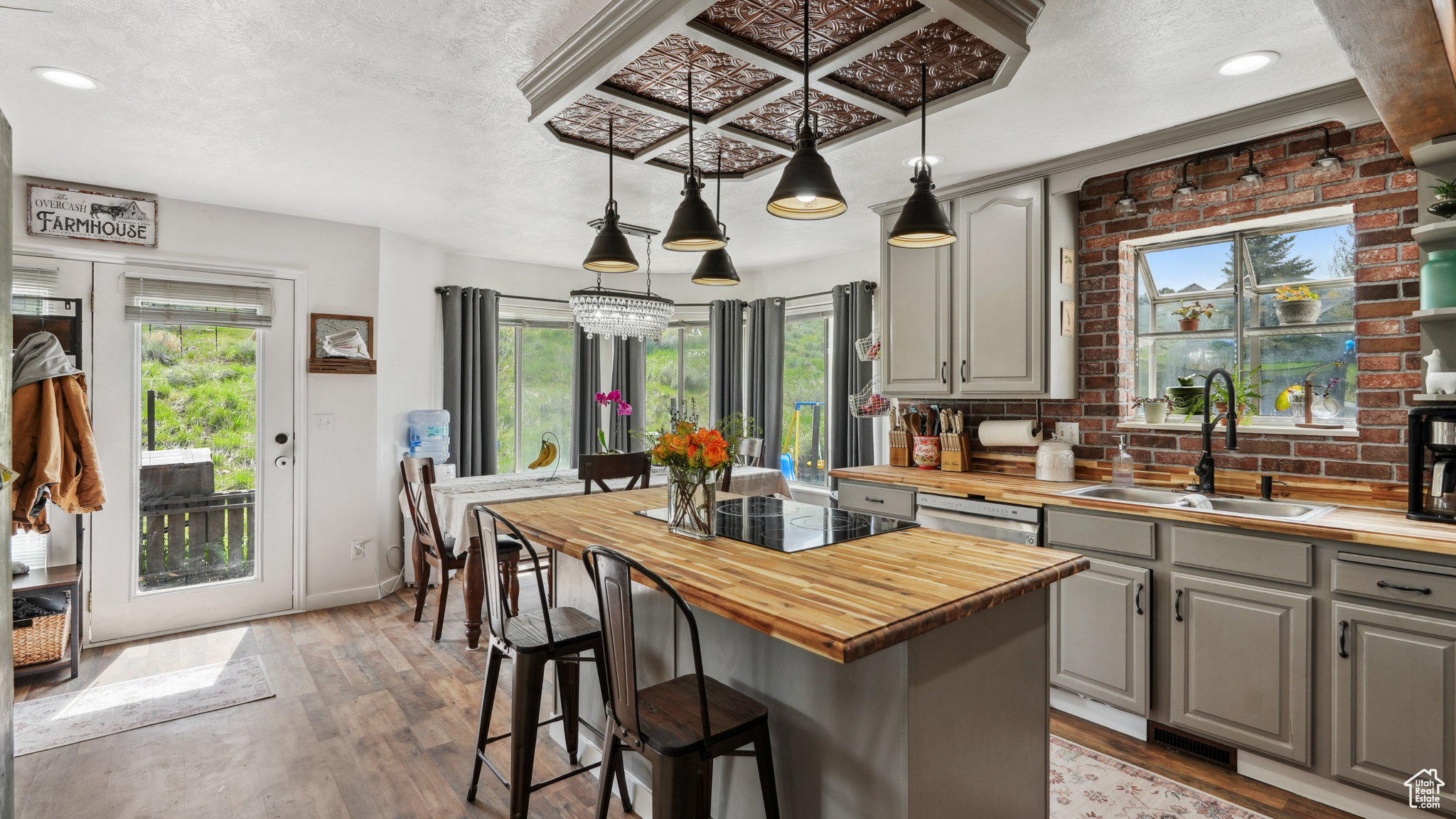 Kitchen featuring a center island, wooden counters, sink, gray cabinets, and pendant lighting