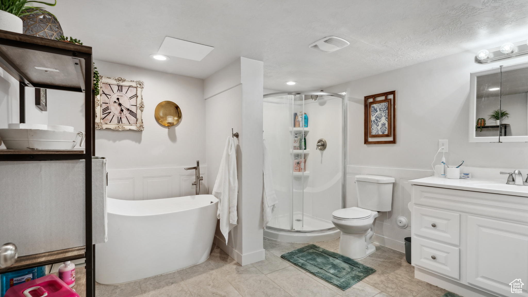 Bathroom featuring a shower with shower door, toilet, tile floors, and vanity