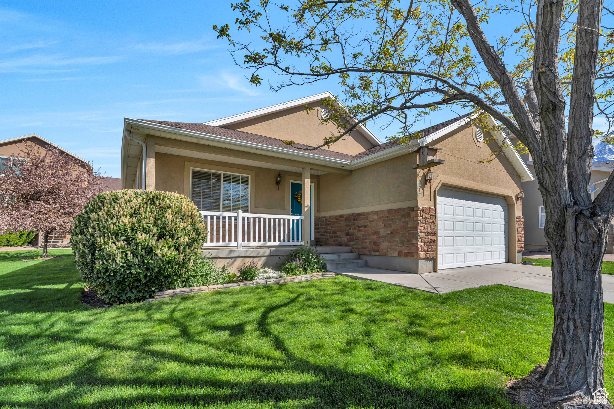 Ranch-style home with a garage, covered porch, and a front lawn