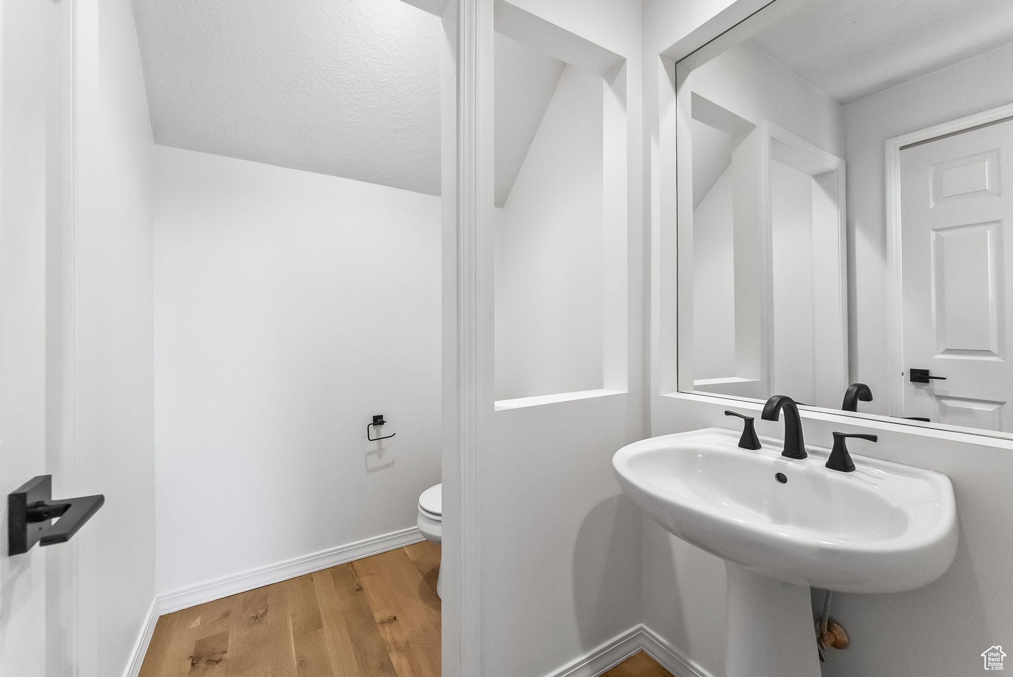Half bathroom featuring hardwood / wood-style floors, Pedestal sink.